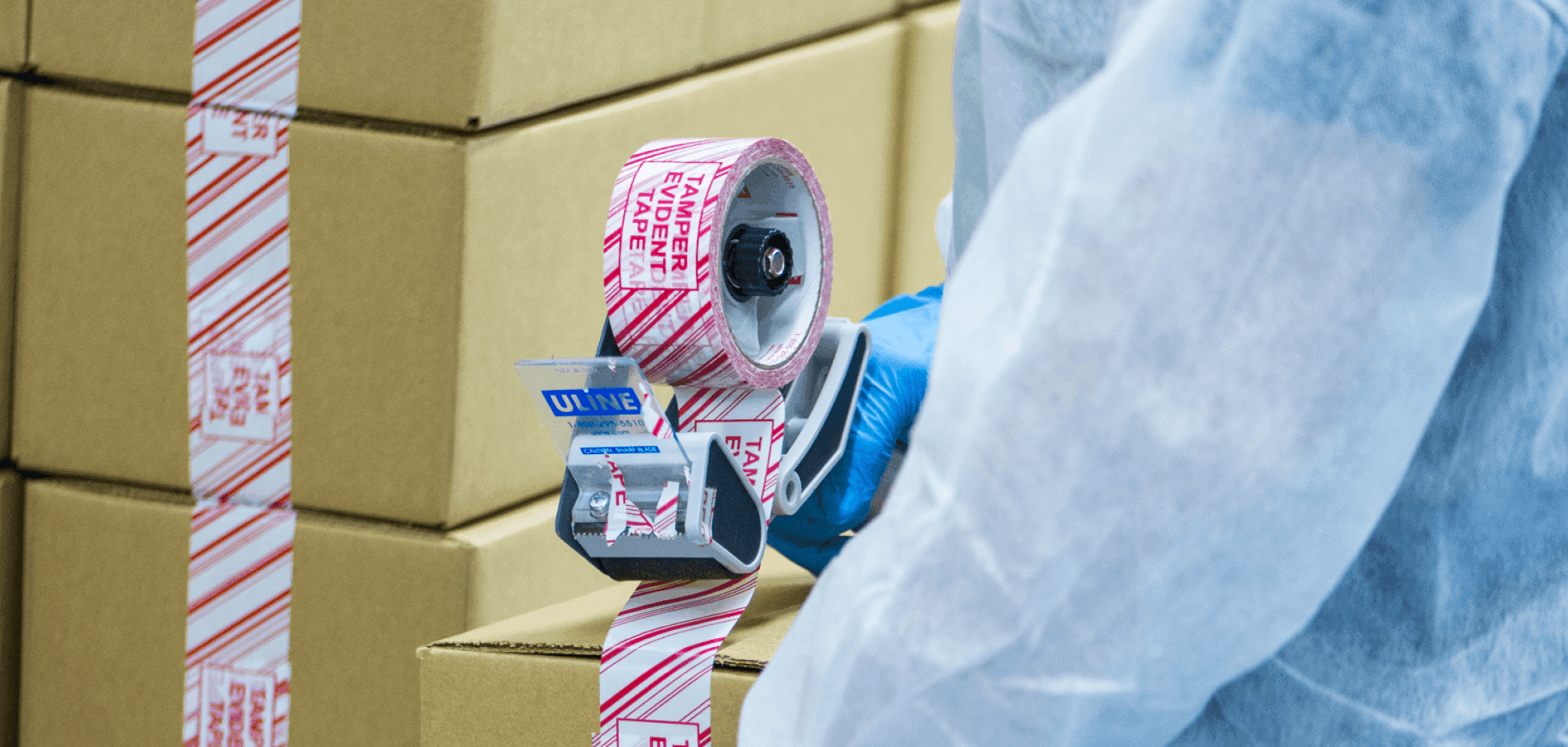 Image of a cannabis lab worker handling a roll of tape during the packaging process